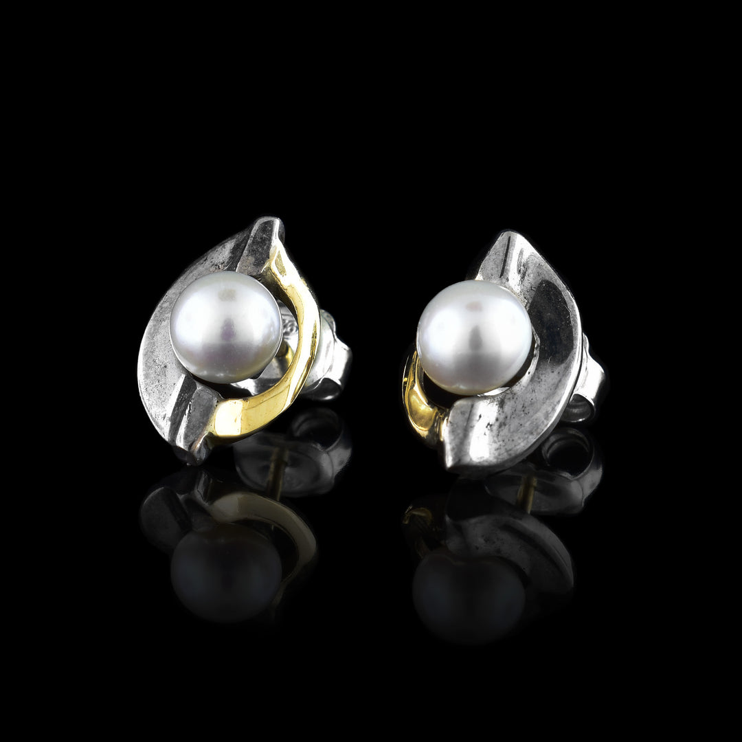 These pearl stud earrings have one sterling silver band and one 14K gold band wrapping around a fresh water pearl in the center of each earring.