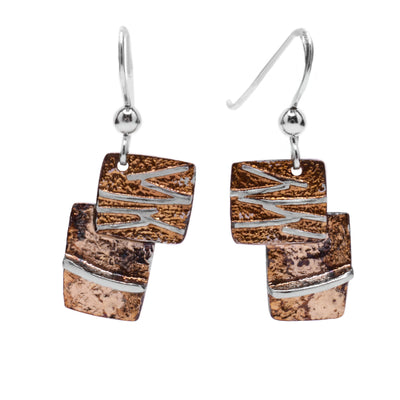These oxidized silver earrings are in the shape of two small squares with one stacked on top of the other. Each earring is light brown and beige in colour with linear sterling silver accents throughout.