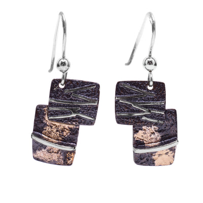 These oxidized silver earrings are in the shape of two squares stacked on top of one another. Each earring is black in colour with 14k gold spots and sterling silver accents throughout.