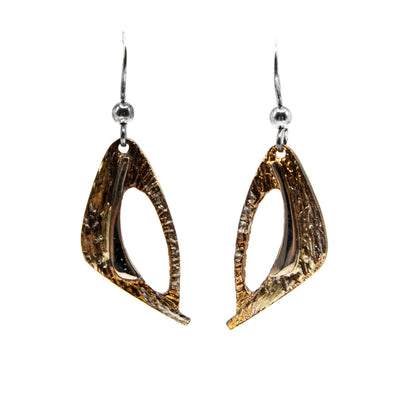 These oxidized silver earrings are shaped like an abstract triangle with a hole off to the side. Each earring is orange and light brown in colour.