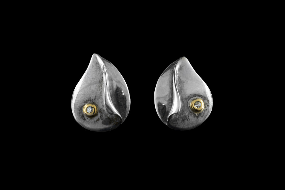 These sterling silver diamond earrings are teardrop shaped and have diamonds wrapped in 14K gold on them.