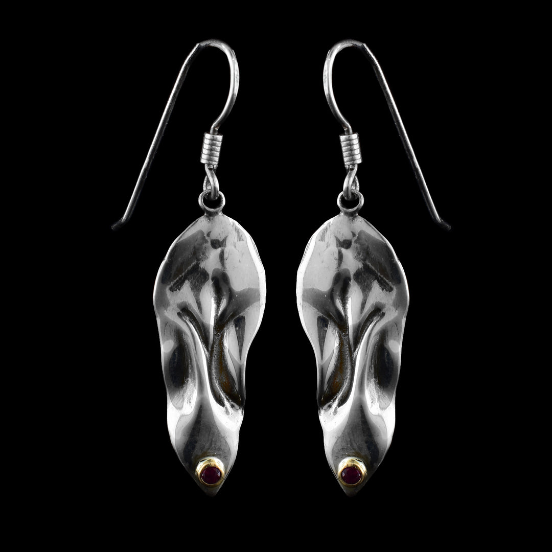These ruby drop earrings have large, sterling silver hangs that have been shaped to have unique folds and wavy designs in them. There are small rubies that are bezel set in 14K gold at the bottom of the hangs.