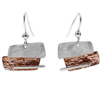 These oxidized silver earrings are in the shape of two rectangular pieces, one sterling silver and one oxidized, joint together. The oxidized bottom pieces is light brown and beige in colour and has a linear silver accent.