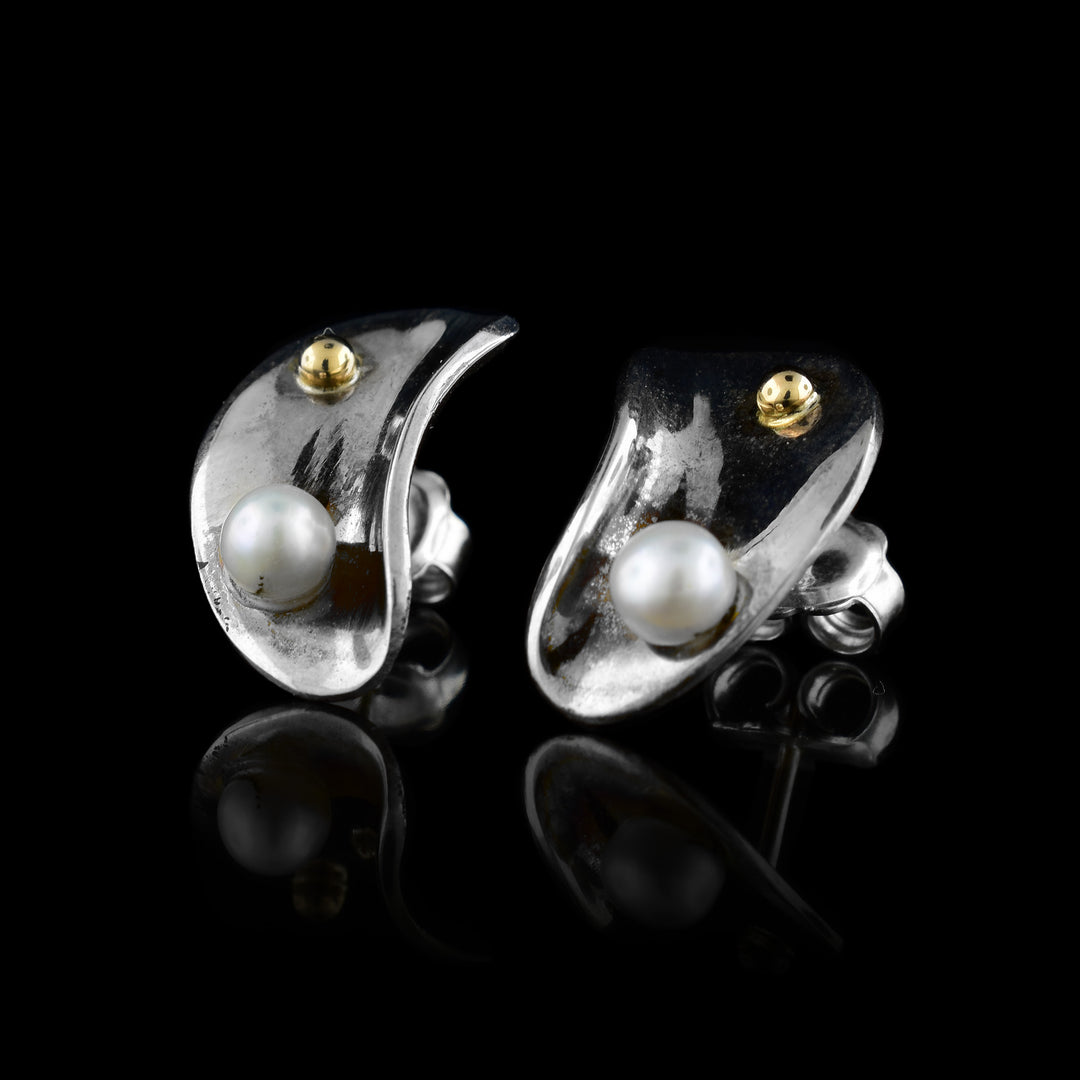 These sterling silver, pearl stud earrings are shaped like shells. On the earrings are a fresh water pearls and 14K gold studs.