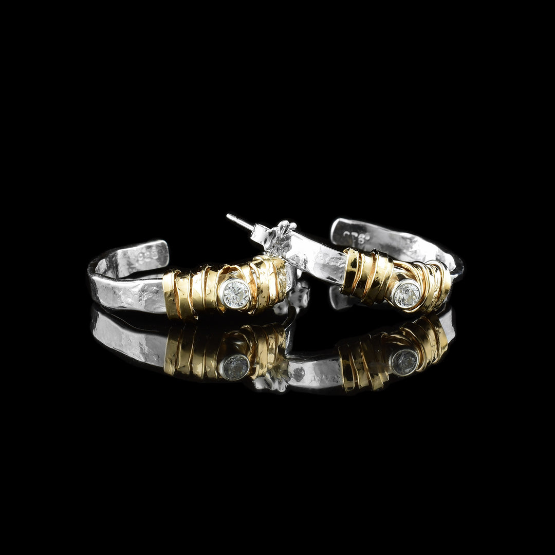 These cubic zirconia hoop earrings have rugged, sterling silver hoops made from a band. There is a cubic zirconia gem held in the hoops and there are 14K gold wraps that are wrapped around the gems.
