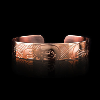 This copper cuff bracelet has a single band with a gap in the back. There is a depiction of the Head of the Eagle that has been carved into the surafce of the band and its wings are depicted stretching across the length of the band.