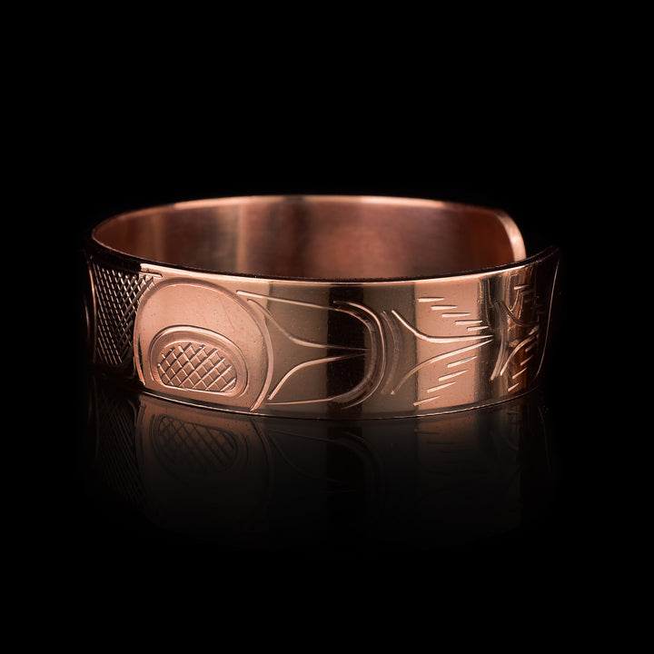 This copper cuff bracelet has a single band with a gap in the back. There is a depiction of the Head of the Eagle that has been carved into the surafce of the band and its wings are depicted stretching across the length of the band.
