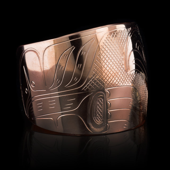 This stunning Eagle bracelet is made using copper and has a single, wide band that tapers slightly and has a gap in the back. There is a large depiction of the Eagle with out-stretched wings beautifully carved into the band. There are cross hatched textures made in the negative space on the piece.