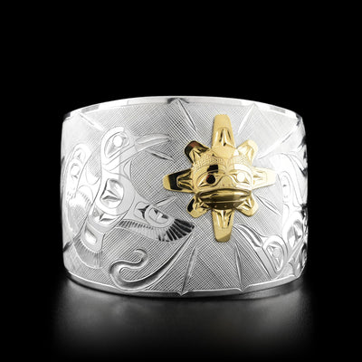This silver cuff bracelet has a raven mid-flight flying towards a sun to the right. The sun is slightly off-center to the right.