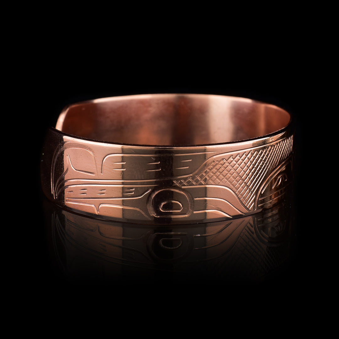 This copper cuff bracelet has a single band with a gap in the back. There is a depiction the Raven that has been beautifully carved into the surface of the band. The head is depicted at the top and its wings are seen at the ends of the band.