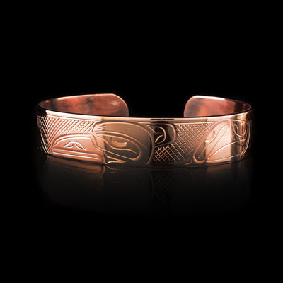 This copper cuff bracelet has a single band with a gap in the back. There is a depiction the Raven that has been beautifully carved into the surface of the band. The head is depicted at the top and its wings are seen at the ends of the band.