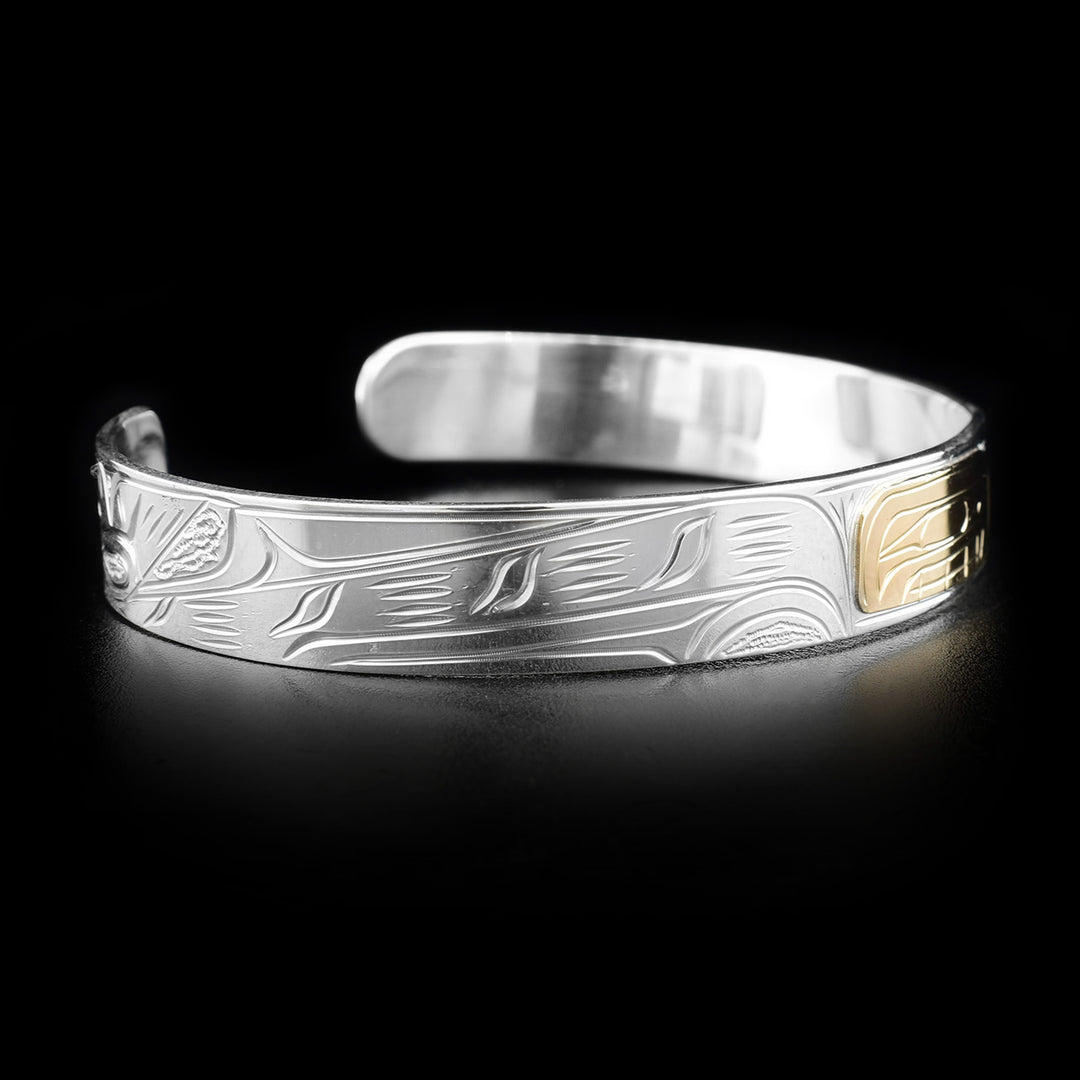 Left angle photo of the bracelet shows carving representing the long body of the main orca with its tail turned upright at the very end.