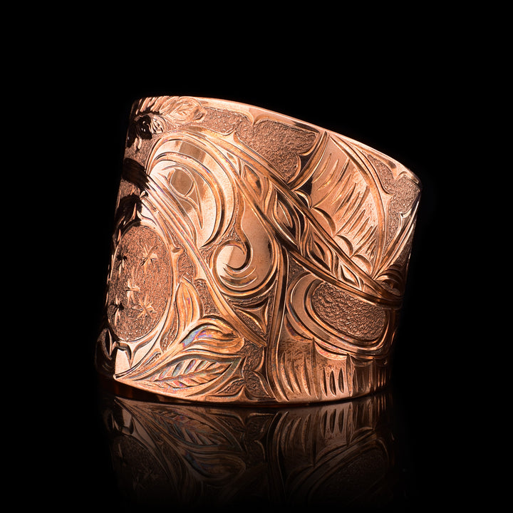 This large copper cuff bracelet has gorgeous carvings across the entire band depicting the Hummingbird, the Moon and floral designs. The band is very wide and tapered.