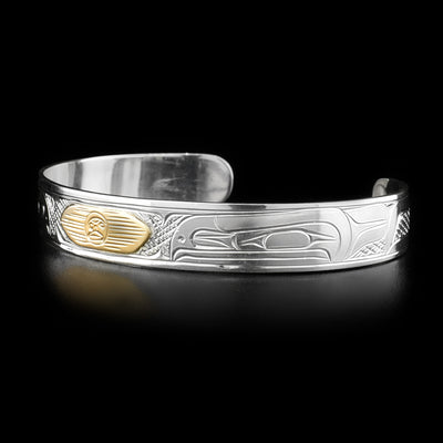 This gold and silver bracelet depicts the heads of two ravens on both the left and right sides of the bracelet facing inwards. In the center is the sun made from gold with a triangular outline.