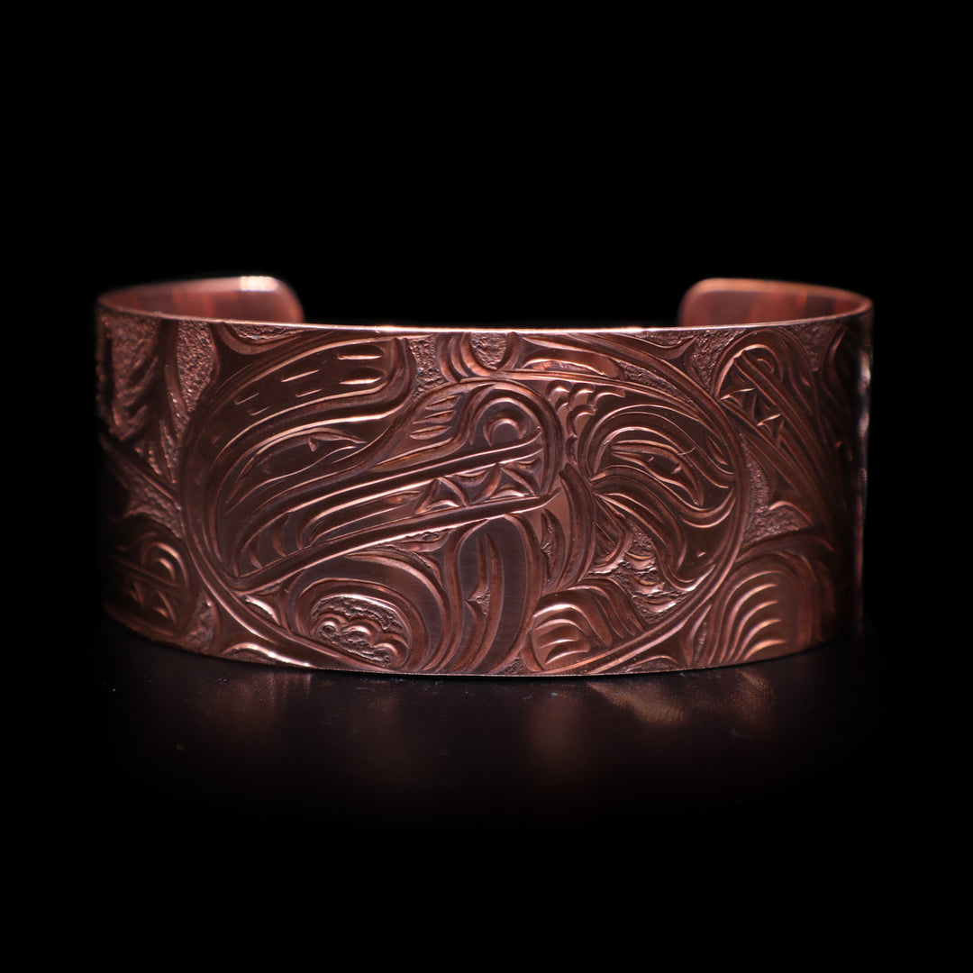 This stunning Bear bracelet is made using copper and has a single, wide band with a gap in the back. There are intricate carvings on the surface of the piece that depicts the Baby Bear in the womb and being watched over by its mother who is depicted in silver and carved on the side of the piece. On the other side of the band, there are depictions of trees.