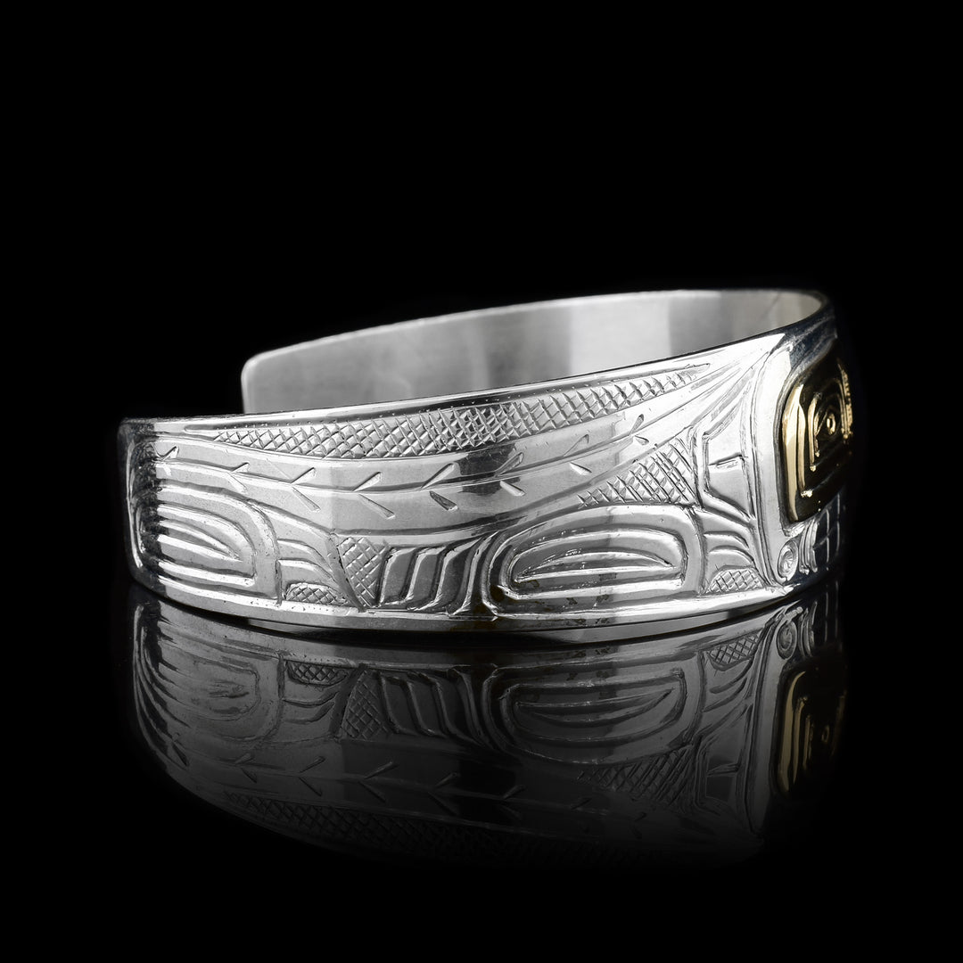 This Raven, Moon and Wolf bracelet has depictions of these legends carved into the surface of it. The band is made from sterling silver and tapers slightly. There are 14K gold embellishments and designs for the eyes of the legends.