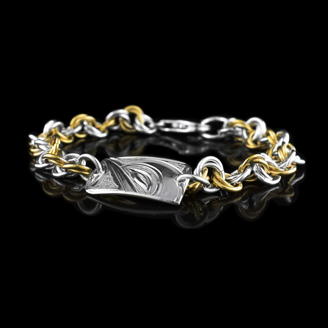This silver and gold link bracelet is made from sterling silver and 14K gold fill. This piece has a silver and gold fill chain with a rectangle charm at the top. There is a depiction of the Hummingbird carved into the surface of the silver charm.