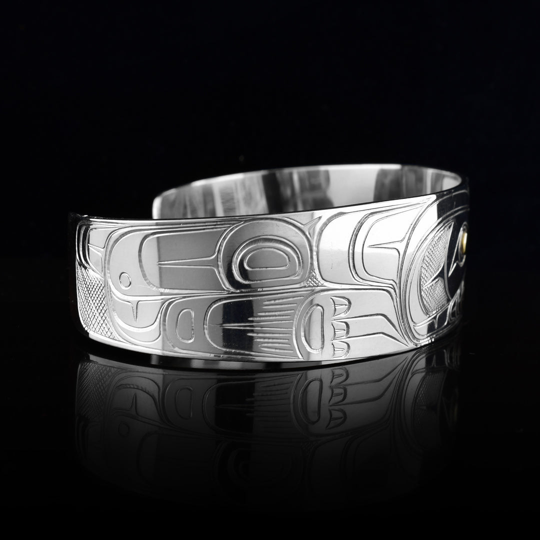 This Wolf bracelet cuff has a single, wide band made from sterling silver. The head of the Wolf is done at a side profile with its ears, snout, eye and teeth detailed. The eye is made using a 14K gold stud and there are paw designs on either side of the head.