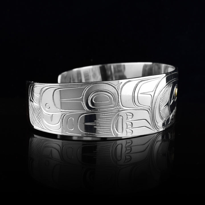 This Wolf bracelet cuff has a single, wide band made from sterling silver. The head of the Wolf is done at a side profile with its ears, snout, eye and teeth detailed. The eye is made using a 14K gold stud and there are paw designs on either side of the head.