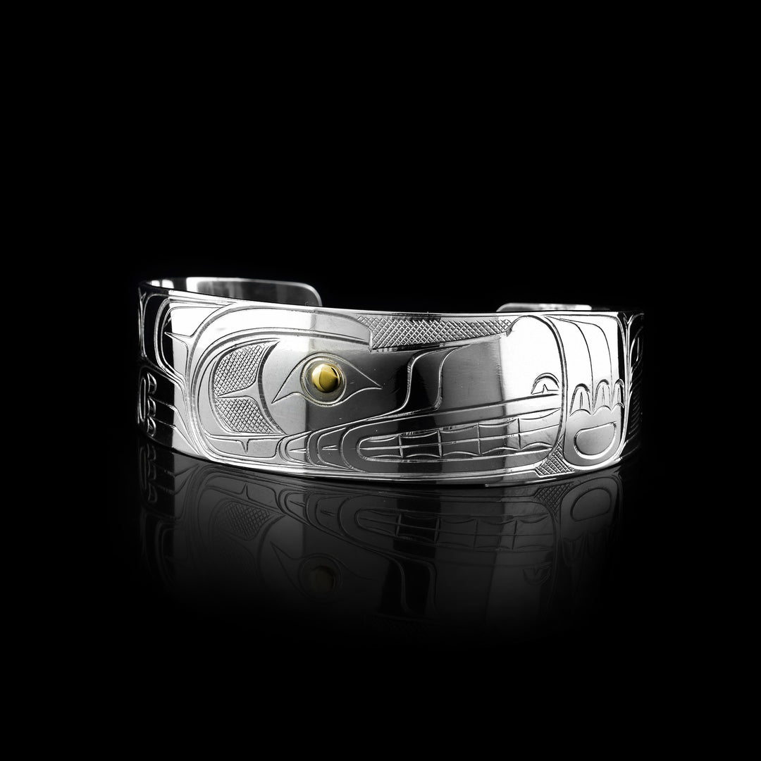 This Wolf bracelet cuff has a single, wide band made from sterling silver. The head of the Wolf is done at a side profile with its ears, snout, eye and teeth detailed. The eye is made using a 14K gold stud and there are paw designs on either side of the head.