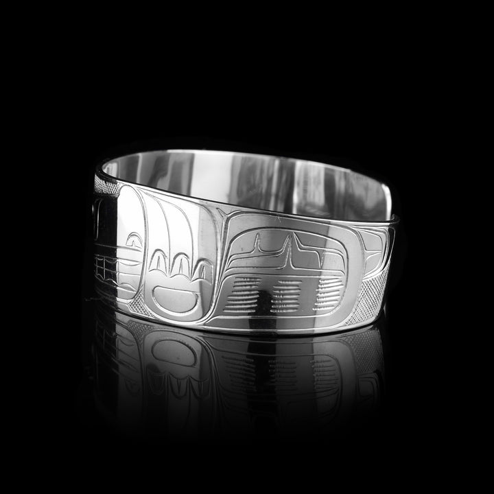 This Wolf bracelet cuff has a single, wide band made from sterling silver. The head of the Wolf is done at a side profile with its ears, snout, eye and teeth detailed. The eye is made using a 14K gold stud and there are paw designs on either side of the head.
