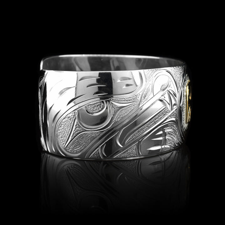 This stunning Bear bracelet is made using sterling silver, 14K gold and has a single, wide band with a gap in the back. There are intricate carvings on the surface of the piece that depicts the Baby Bear, done in gold, in the womb and being watched over by its mother who is depicted in silver and carved on the side of the piece. On the other side of the band, there are depictions of forest trees.