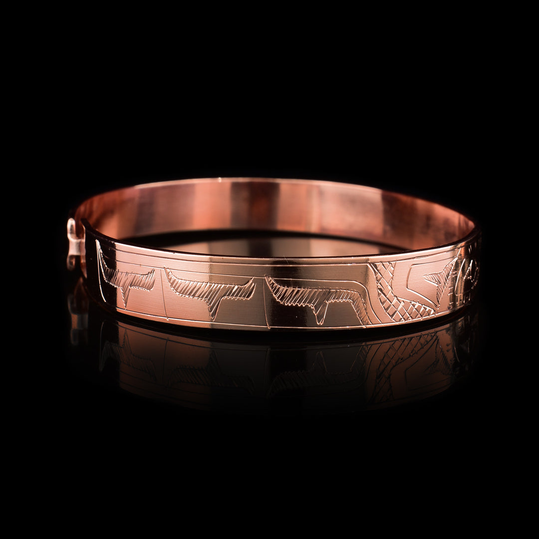 This copper bangle bracelet has a single, thin band with a simple hook clasp in the back. There is a depiction of the Hummingbird and the Eagle that have been beautifully carved into the surface of the band. The heads of the legends meet and are facing each other at the top f the band.