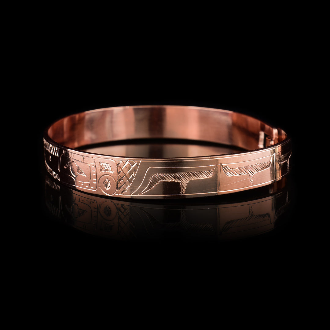 This copper bangle bracelet has a single, thin band with a simple hook clasp in the back. There is a depiction of the Hummingbird and the Eagle that have been beautifully carved into the surface of the band. The heads of the legends meet and are facing each other at the top f the band.
