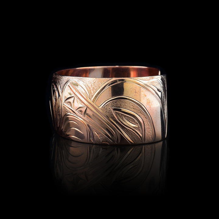 This stunning Wolf bracelet is made using copper and has a single, wide band with a gap in the back. I the center of the band, there is the head of the Baby Wolf placed in the middle of an oval design which represents the womb. On the right end of the band, the mother wolf is depicted with the side profile of her head which is tilted upwards. On the other end of the band there are simple pine trees carved into the band