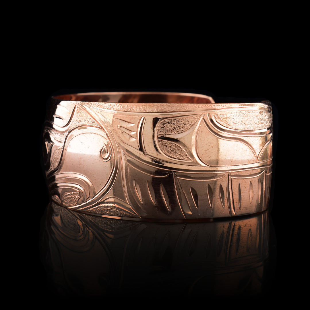 This Eagle cuff bracelet has a single, wide band with a gap in the back that is made from copper. The head of the Eagle is carved into an oval shaped at a side profile. On both ends of the band, there are outstretched wings with feather details included.