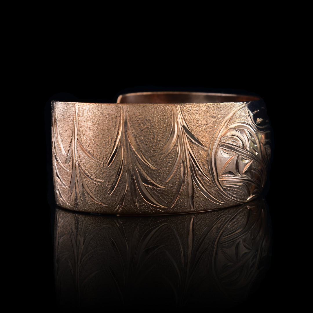 This stunning Bear bracelet is made using copper and has a single, wide band with a gap in the back. In the center of the band, there is the head of the Baby Bear placed in the middle of an oval design which represents the womb. On the right end of the band, the mother Bear is depicted with the side profile of her head which is tilted upwards. On the other end of the band there are simple pine trees carved into the band