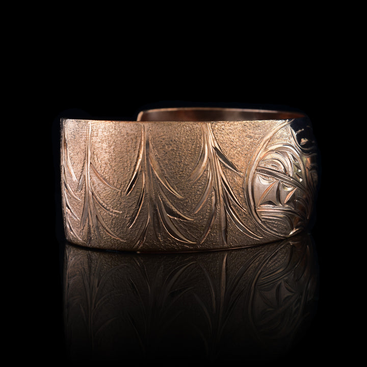 This stunning Bear bracelet is made using copper and has a single, wide band with a gap in the back. In the center of the band, there is the head of the Baby Bear placed in the middle of an oval design which represents the womb. On the right end of the band, the mother Bear is depicted with the side profile of her head which is tilted upwards. On the other end of the band there are simple pine trees carved into the band