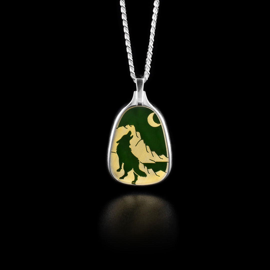 This jade Wolf pendant has the design of a wolf howling at a crescent moon with mountains in the background.