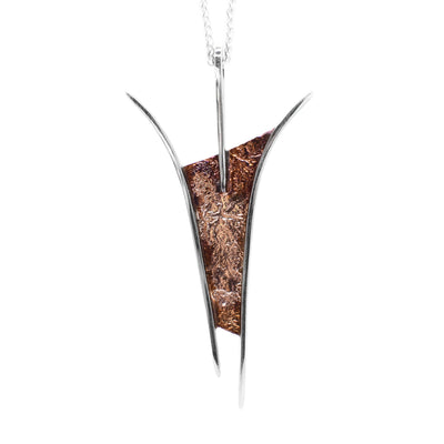 This oxidized silver necklace is in the shape of a curved rectangle. The middle of the pendant is varying shades of brown in colour and has thin sterling silver accents encasing it on each side.