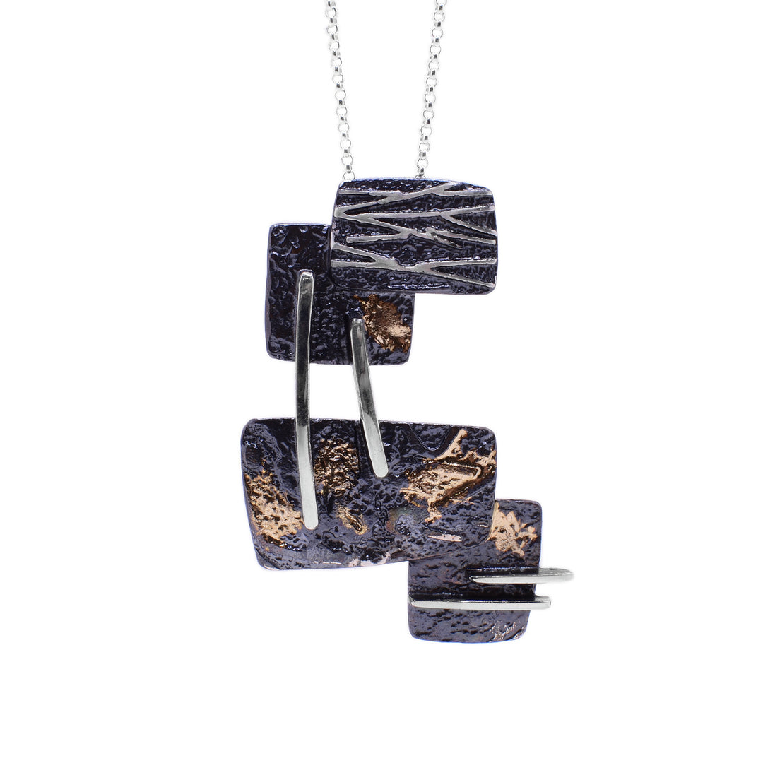 This oxidized silver necklace is made up of four square-shaped dark oxidized silver layered on top of one another with sterling silver accents and spots of 14k yellow gold.