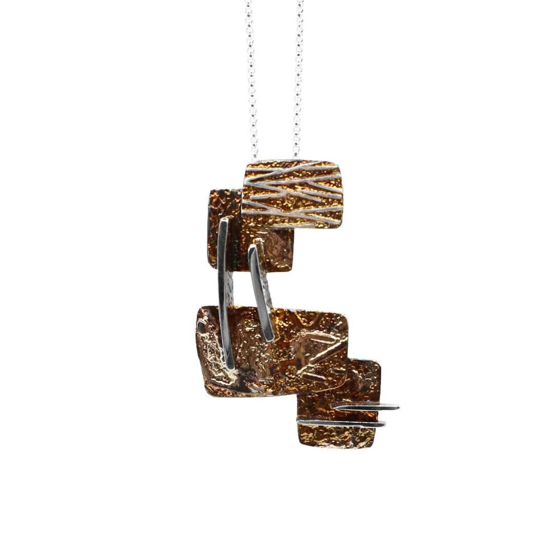 This oxidized silver necklace has 4 oxidized pieces of silver layered on top of one another with abstract silver lines placed throughout.