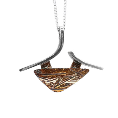 This oxidized silver necklace is in the shape of a downward arrow with two abstract silver lines. The oxidized silver is orange and brown in colour.