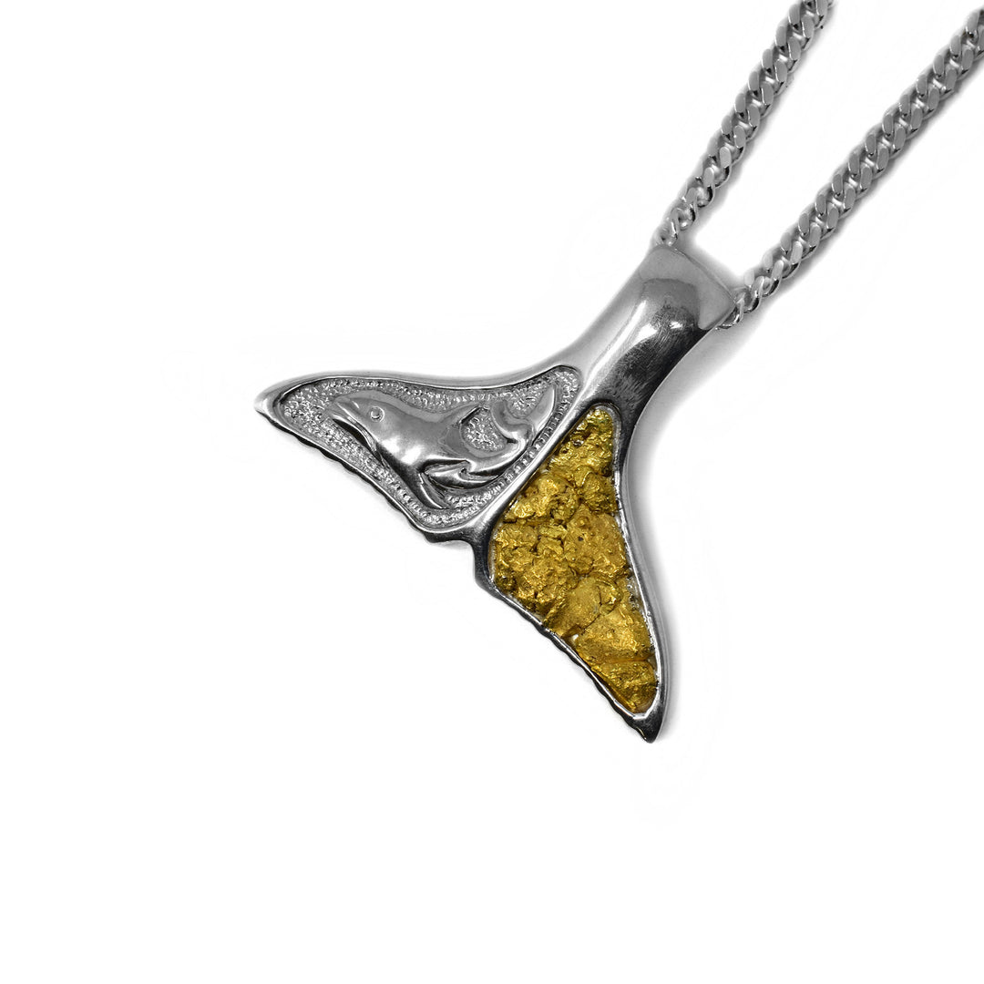This whale tail pendant has it's left fin filled with 22K gold nuggets and it's right fin has the side-view of a swimming whale against a textured background carved into it.