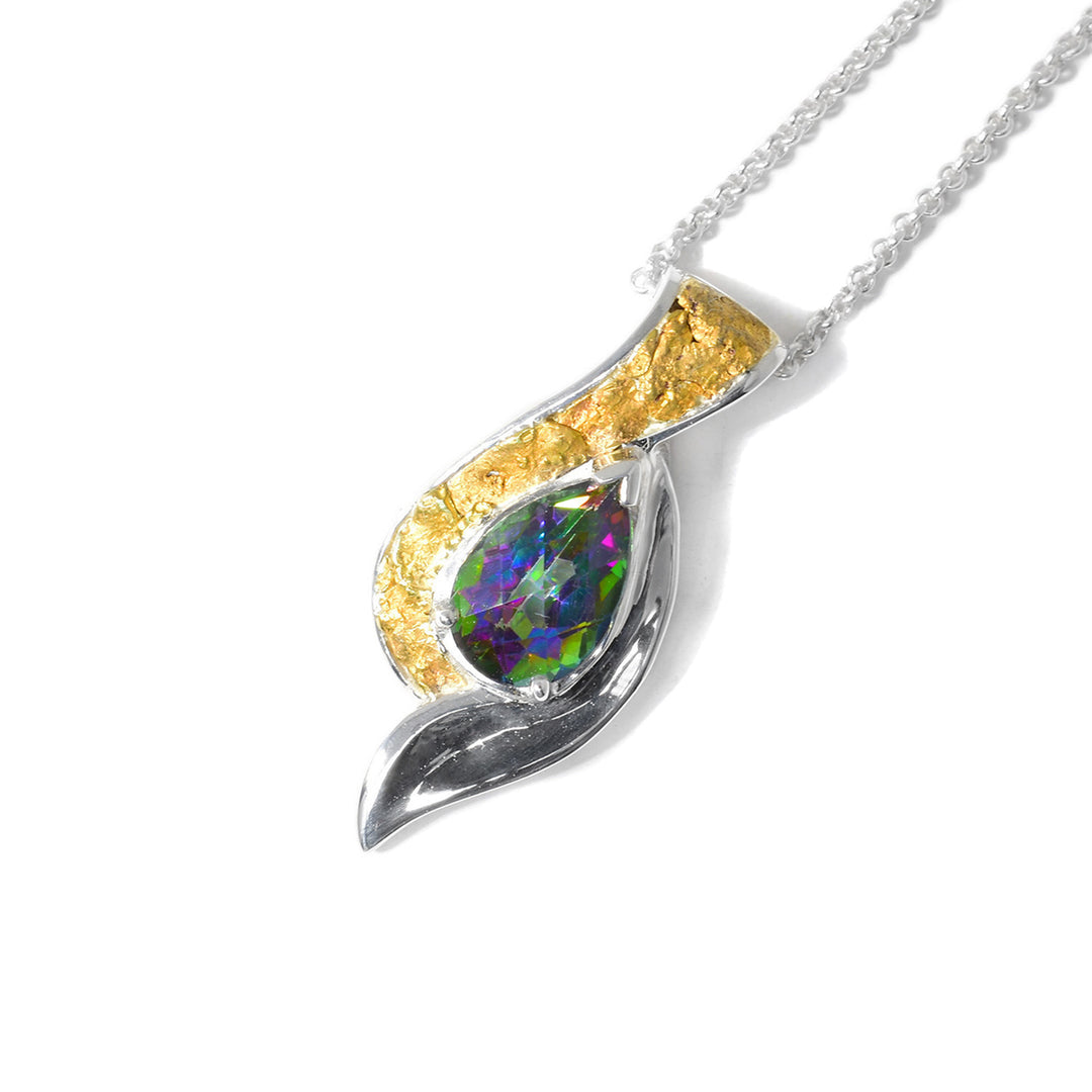 This blue topaz gold pendant is unique in shape, mimicking a yin and yang shape with the pear-shaped topaz in the center. The left side is made entirely of gold nuggets and to the right of the topaz is purely silver.
