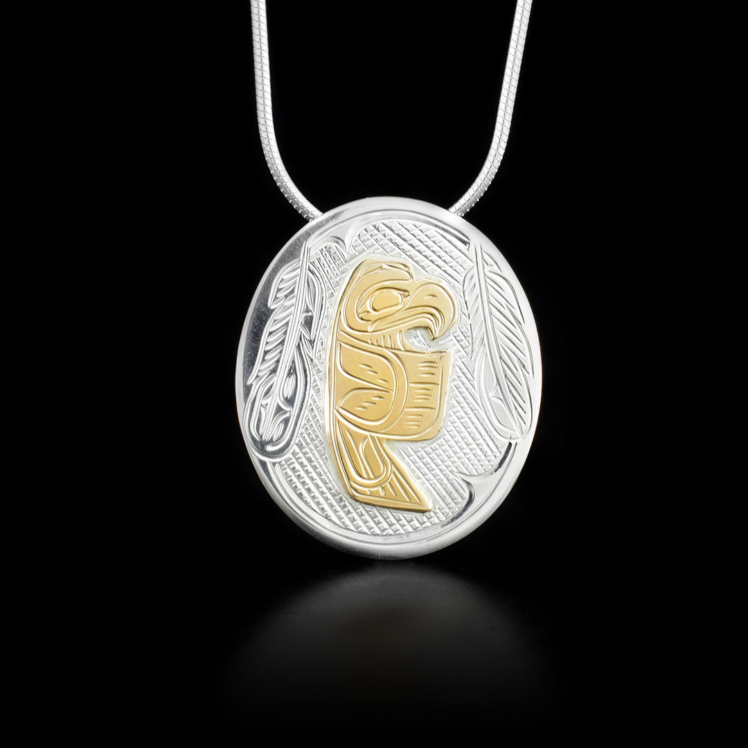 This eagle necklace is oval in shape and depicts the side view of a full-bodied eagle made from gold. Its head is in the center with its wing and tail underneath. Two feathers have been carved on both sides of the eagle. Background is cross-hatched.
