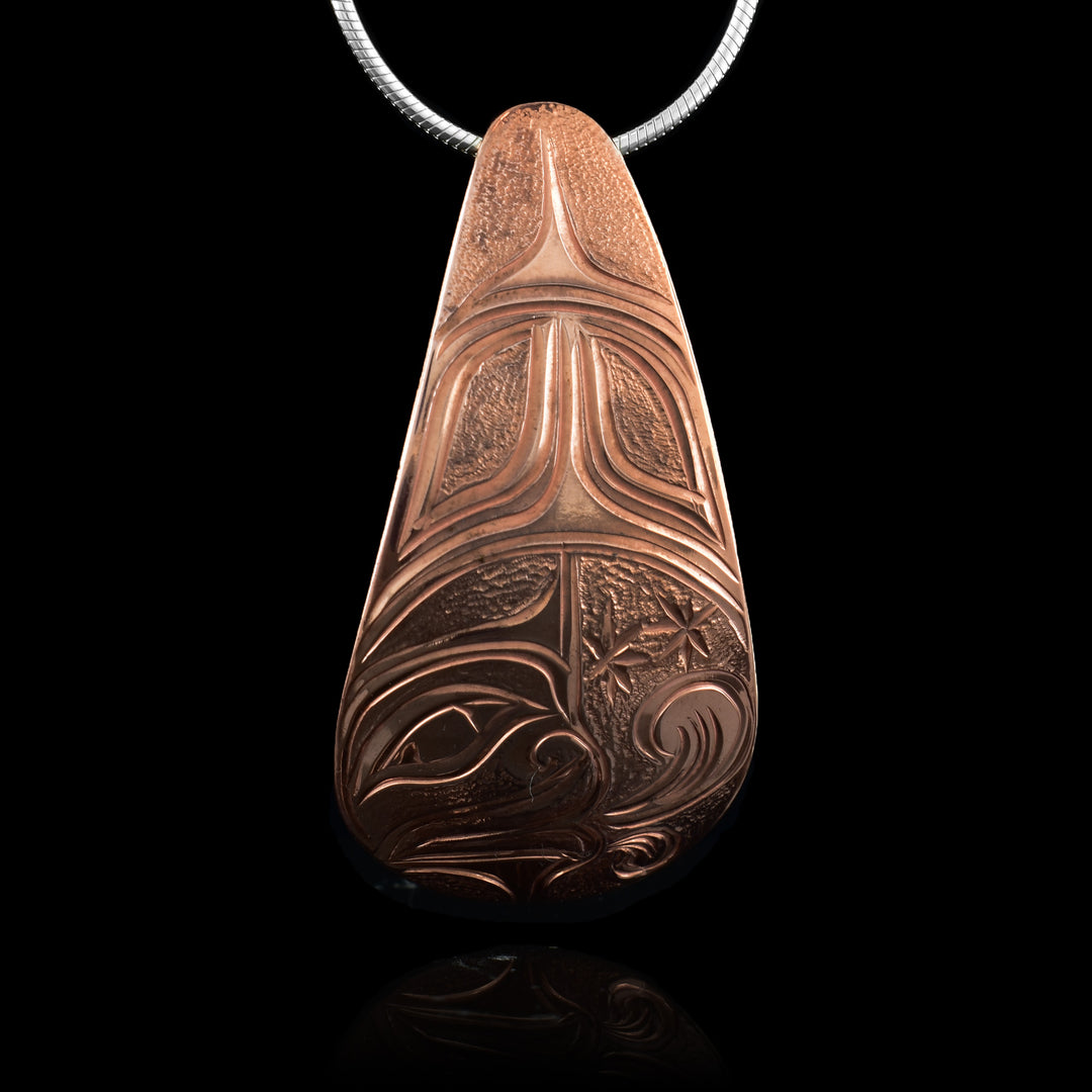 This Wind Spirit pendant is made from copper and has a long, wide teardrop shape. At the bottom of the piece, there is a depiction of the wind spirit in a circle. There are stars around the spirit and its face (shown at a side profile) has wind coming out of the mouth. The top of the pendant has abstract design with dimpled textures made as highlights.