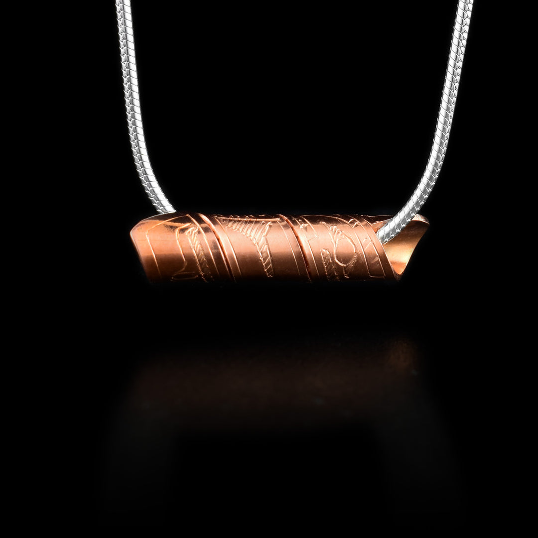 This spiral cylinder pendant is made from a single, copper band that has been twisted into a cylinder. There is depiction of the Eagle legend carved into the surface of the band so it appears on the outside of the cylinder. It is shown at a side profile with its head, eye and beak at one end and wing details behind it.