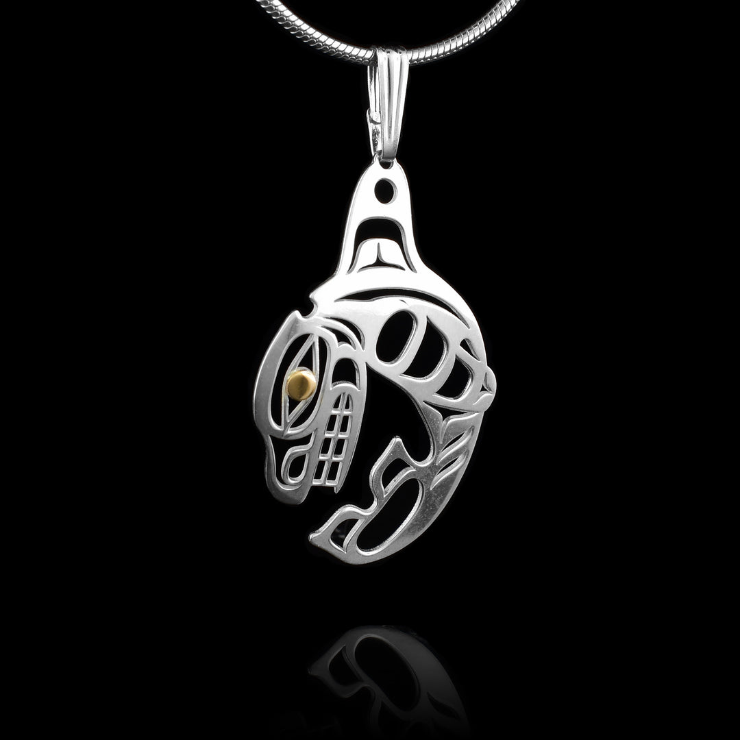 This cresting Orca pendant is made from sterling silver and is shaped like the Orca legend breaching through the water. The head curls down and ends near the tail while the dorsal fin is at the top of the piece. The details of the whale are made from cutouts all around the piece and the eye is done in 14K gold.