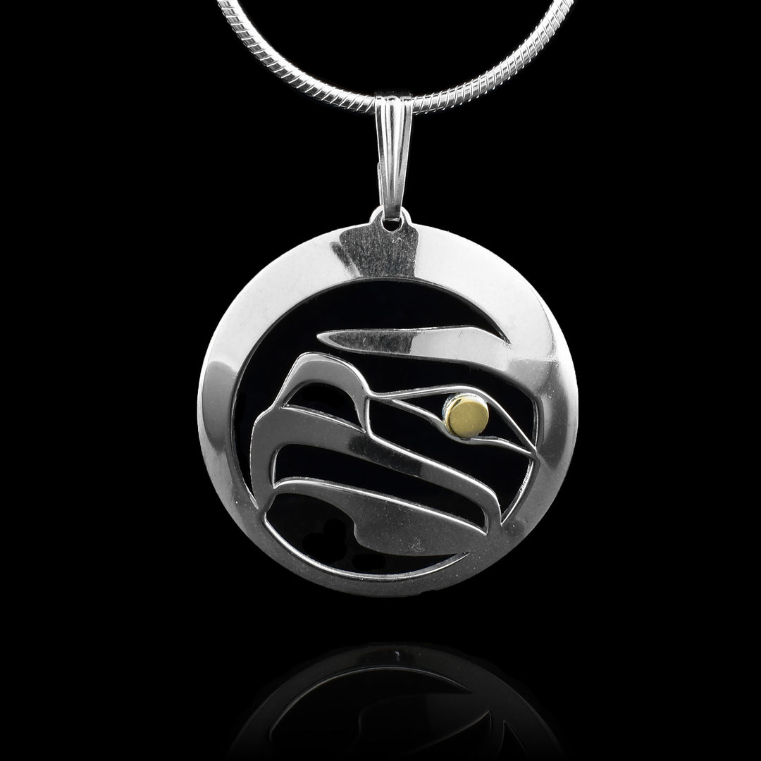 This Eagle pendant has a circle ring made from sterling silver with a cutout depiction of the Eagle in the center of it. The cutout shows details of the head of the Eagle at a side profile with its nose, eye and beak. The eye is done using 14K gold.