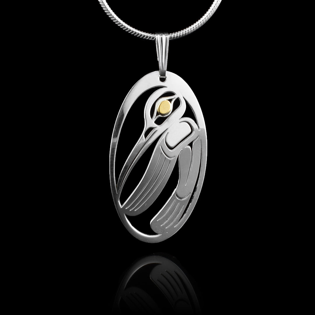This Hummingbird pendant has a long, thin and oval shape with a cutout depiction of the Hummingbird on it. The Hummingbird is done at a side profile with its head at the top and its long beak extends across the piece. Its wing and tail are at the bottom and its eye is done in gold.
