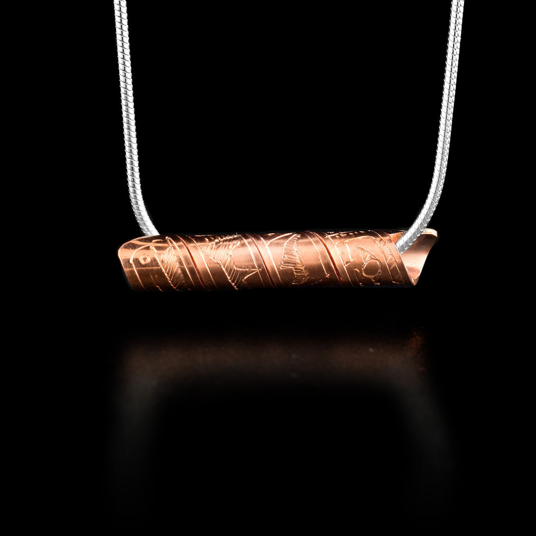 This spiral cylinder pendant is made from a single, copper band that has been twisted into a cylinder. There is depiction of the Raven legend carved into the surface of the band so it appears on the outside of the cylinder. It is shown at a side profile with its head, eye and beak at one end and wing details behind it.