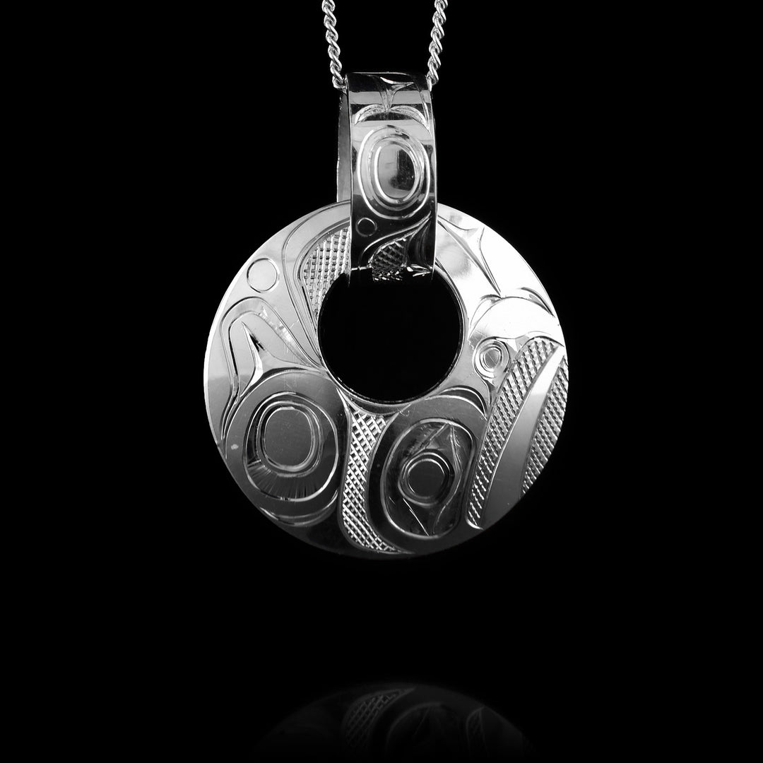 Crafted by Haida artist Jim McGuire, this sterling silver open circle pendant features a decorative bail and an intricate carving of the Raven legend. It’s a bold, beautiful piece designed to be noticed.