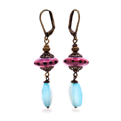 Antiqued brass earrings that feature raspberry disk-shaped handmade lampworked glass beads with black dots. Faceted oval blue chalcedony dangles below. By Wendy Pierson. Lever-back hooks.