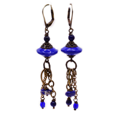 For each earring, there is a big, horizontal disc-shaped dark blue lampworked bead with dangling blue and lapis beads below. Metal is brass.