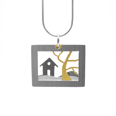 Rectangular, horizontal grey frame with grey house and gold-coloured tree inside. House and tree are on grey and silver-coloured hills. Stainless steel snake chain included. Minimalist design. By JR Franco.